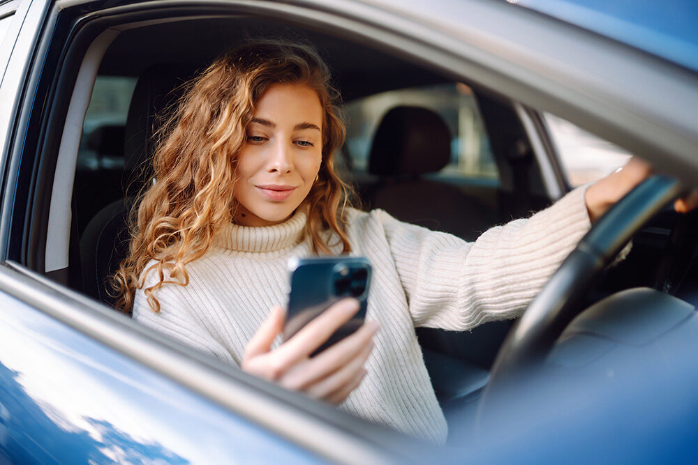 Woman in car looking at her smartphone