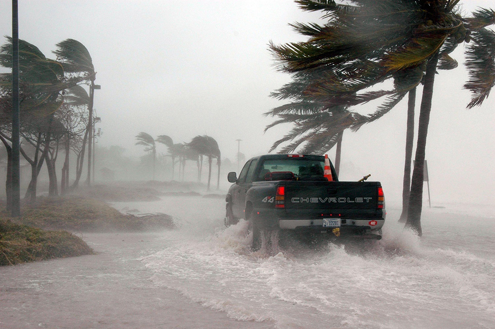 Climate change travel pickup truck in flood and storm winds