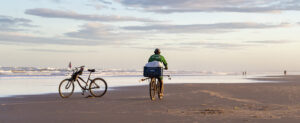 Where in the World 566 man riding a bicycle along a beach featured image
