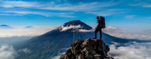 Where in the World 617 featured image man on mountain peak above the clouds