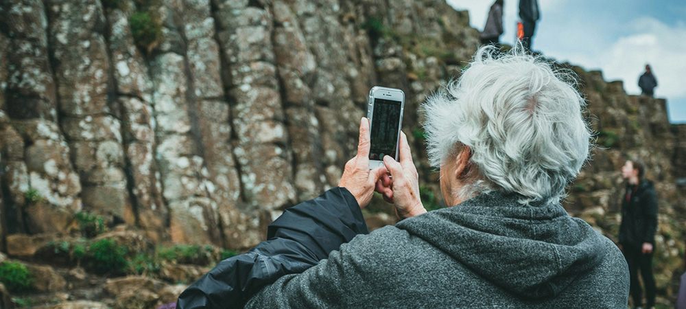 Solo travel in retirement senior using a smartphone to take a photograph