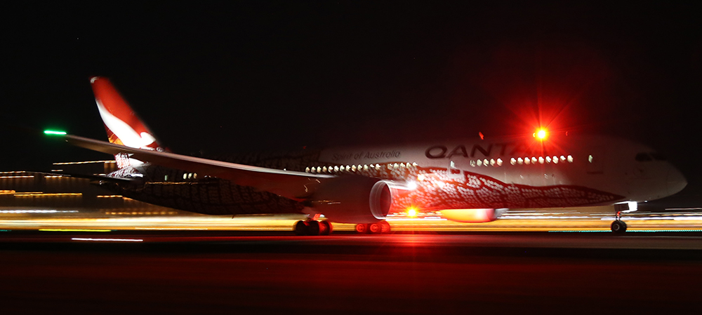 Long haul flights - night time shot of Qantas Dreamliner departing LHR