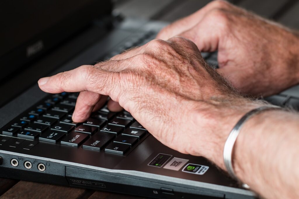 Hands of a senior retiree typing ona laptop computer